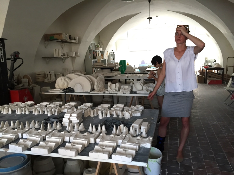 Daniel Pirsc's wife in his porcelain workshop with moulds on table